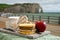 Cheeses of Normandy, round camembert cow cheese, yellow livarot, heartshaped neufchatel and view on alebaster cliffs Porte d`Aval