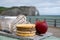 Cheeses of Normandy, round camembert cow cheese, yellow livarot, heartshaped neufchatel and view on alebaster cliffs Porte d`Aval