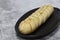 Cheesy garlic bread baton baguette with herbs on a black granite plate.