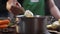 Chef adds cream cheese to the meal while cooking, the cook puts some ricotta to the stainless pan, making the mashed