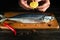 Chef adds fresh lemon juice to raw mackerel fish before cooking with ingredients and aromatic spices