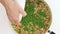 Chef adds green peas into frying pan with mix of couscous, orzo, and shrimp.