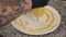 The chef applying yellow sauce to the pizza dough in the restaurant kitchen.