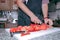 Chef in apron cutting peeled tomato on a board in the kitchen