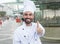 Chef with beard showing thumb in front of a restaurant