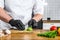 A chef in black gloves prepares guacamole from fresh avacado Hass