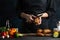 Chef in black peels potatoes on the restaurant`s kitchen isolated on dark background. Cooking tasty dish with potatoes. Girls