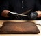 Chef in a black shirt and black latex gloves sharpen a kitchen knife on an iron sharpener