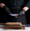 Chef in a black shirt and black latex gloves sharpen a kitchen knife on an iron sharpener with a handle