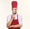 Chef in burgundy apron and hat holds sharp knife.