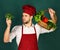 Chef in burgundy uniform looks at broccoli an hand.