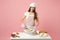 Chef cook confectioner or baker in white t-shirt toque chefs hat cooking at table isolated on pink pastel background in