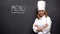 Chef-cook posing near Menu word, resort city restaurant, exclusive cuisine