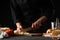 Chef, cook prepares an Italian dish of lasagna, slices onions. Black background. Cooking method. Culinary, gastronomy, restaurant