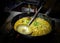 A chef cooking tadka fry in a frying pan at a road side food corner on a stove over flames