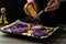 Chef cooking vegetables dish of red cabbage baked with nuts, quince and apples, flying grated cheese scattering in a freeze motion