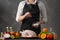 Chef cooks chicken for baking, sprinkling salt with Frost in motion. Against the background of a gray wall. Vegetables and fruits