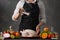 Chef cooks chicken for baking, sprinkling salt with Frost in motion. Against the background of a gray wall. Vegetables and fruits