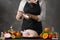 Chef cooks chicken for baking, sprinkling salt with Frost in motion. Against the background of a gray wall. Vegetables and fruits