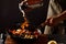 Chef cooks with fire in a pan shrimp with vegetables. On a black background