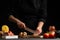 Chef cooks Italian pizza by slicing fresh mushrooms. Against the background of pizza ingredients. Black background, horizontal