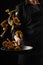 Chef cooks seafood, fry shrimps. Freezing in motion on a black photo, vertical photo
