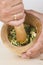 Chef crushing garlic and parsley with mortar and pestle in the k