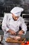 Chef cut beef at kitchen restaurant. Chef male cutting beef at kitchen table.