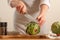 Chef cuts artichoke on a light background, concept cooking tasty and healthy food, menu, recipe book, detox, restaurants, Close-up