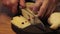 A chef cuts cheese on a black cutting board.