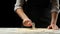 The chef cuts Italian pasta from dough. Against a dark background. A concept of preparing delicious food, Italian cuisine and