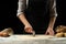 The chef cuts Italian pasta from dough. Against a dark background. A concept of preparing delicious food, Italian cuisine and