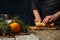 Chef cuts with knife apple on wooden chopped board for preparing aromatic muled wine with fragrant species on christmas