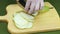 The chef cuts the pear into slices with a very sharp knife on a wooden board