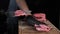 Chef cuts a piece of raw meat on a wooden board