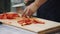 Chef cuts red pepper on cutting board in industrial kitchen