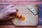 Chef is cutting carrot on a wooden cutting board with sharp knife and word chef written with box letters.