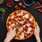 Chef cutting freshly prepared pizza into slices