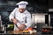 Chef cutting meat at kitchen. Chef in uniform cut beef at planked.