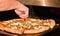 Chef cutting slices of a baked pizza with a pizza cutting wheel