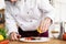 Chef with diligence finishing dish on plate, fish with vegetables