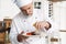 Chef with diligence finishing dish on plate, fish with vegetables