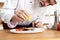 Chef with diligence finishing dish on plate, fish with vegetables