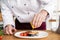 Chef with diligence finishing dish on plate, fish with vegetables