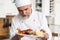 Chef with diligence finishing dish on plate, fish with vegetables