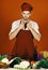 Chef with face poses in uniform on red background. Cuisine and professional cooking concept. Man in cook hat