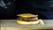 The chef forms a burger with ready-made ingredients, a cutlet lies on a half of the bun and two slices of cheese are