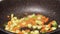 Chef frying carrot, spring onion and baby corn in pan close-up. Woman chief cooking dish with grilled vegetables, vegetarian food.