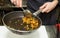 Chef is frying vegetables with herbs