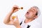 A chef with a funny expression trying honey from a bowl on a white background.